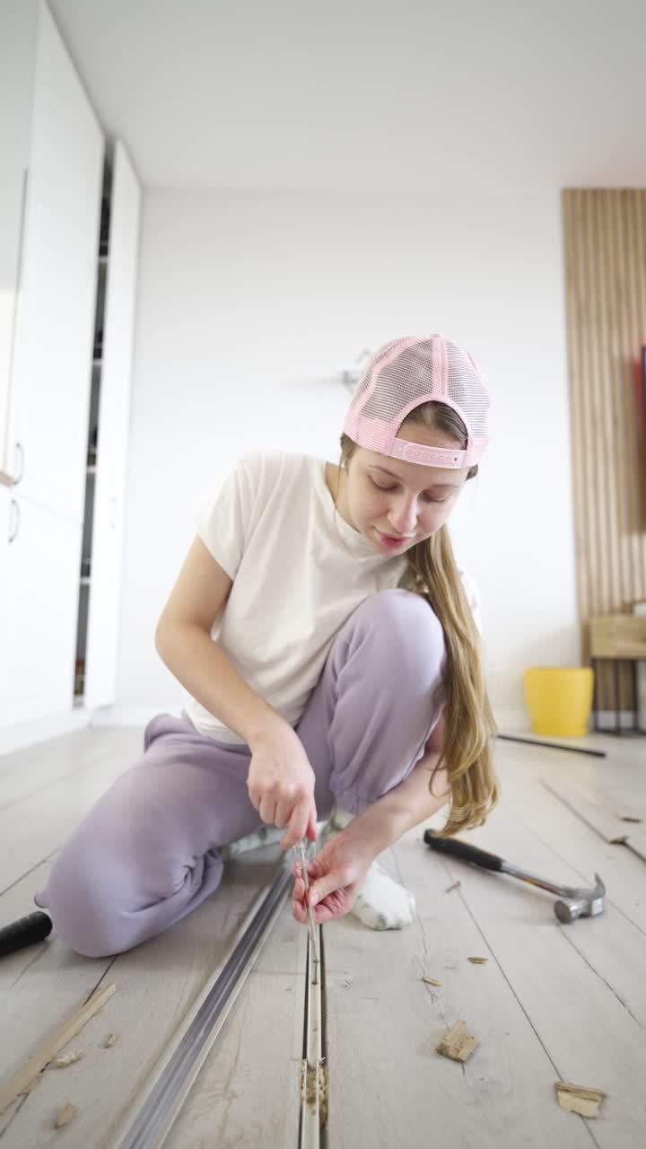Video verticale mostra una donna che installa un profilo di transizione per pavimenti con un cacciavite manuale, focalizzandosi su lavori pratici di fai da te, miglioramento domestico e attività di riparazione interna.