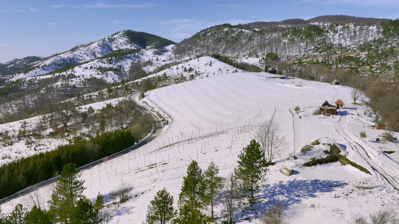 Aerial View of a Snowy Mountain Landscape with a Vineyard and Winding Road