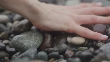 manos tocando guijarros en la playa de piedra