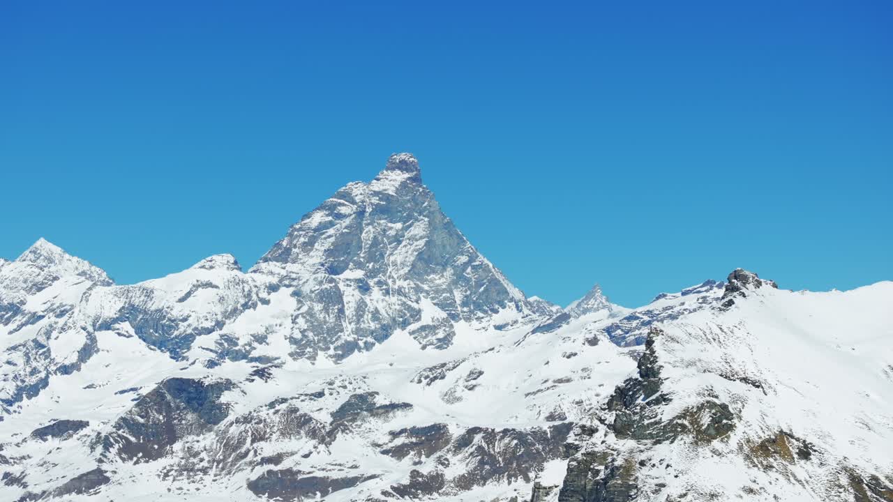 Matterhorn or Cervino mountain under clear blue sky, peak snowy Alps, Cheneil, Italy. Aerial drone, low angle, copy space