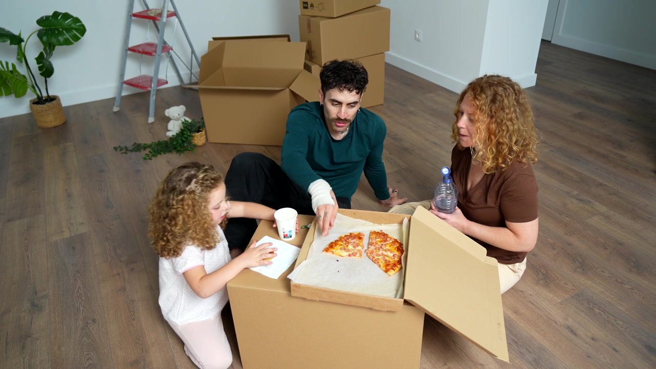 Young Family Eating Pizza on the Floor in Their New Home
