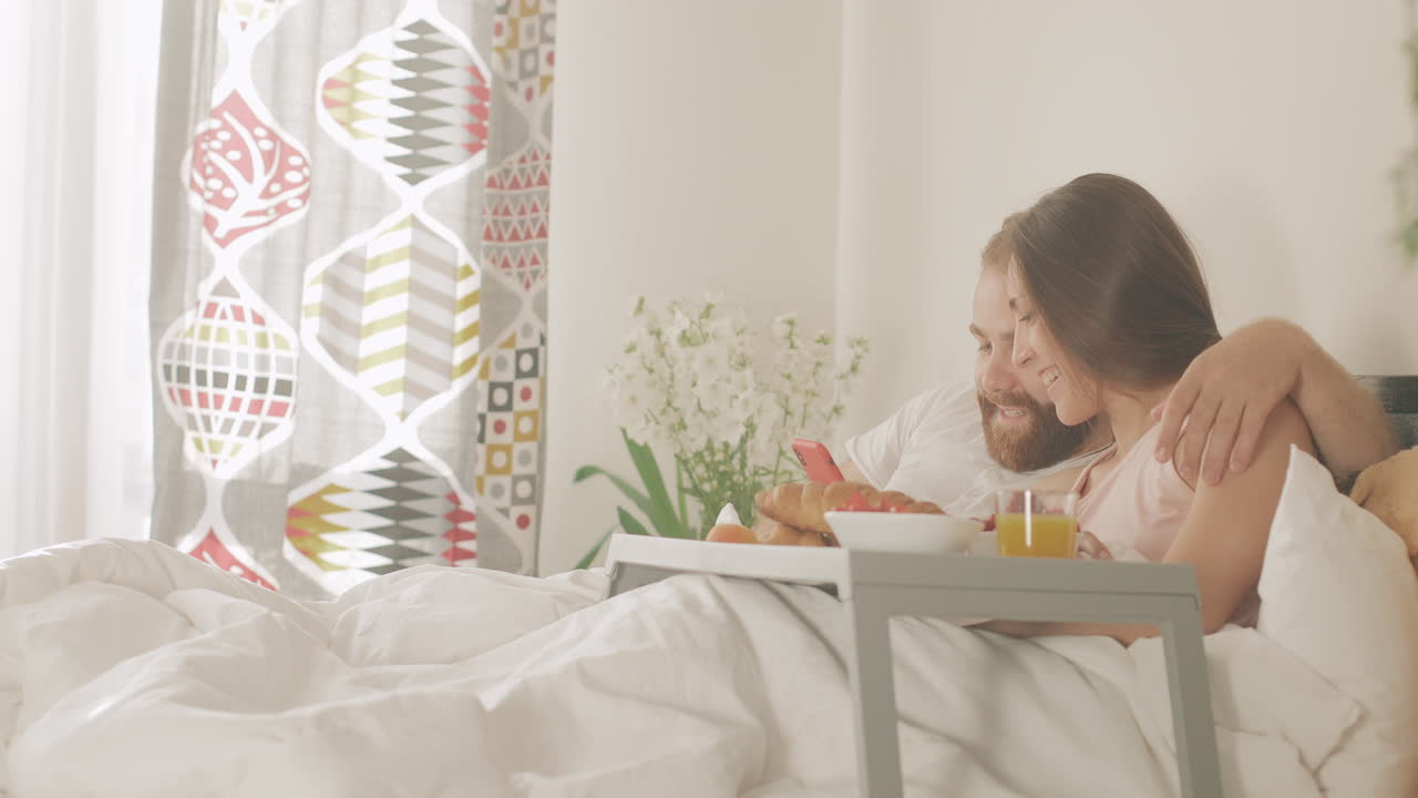 Coppia felice che fa un selfie a letto durante la colazione