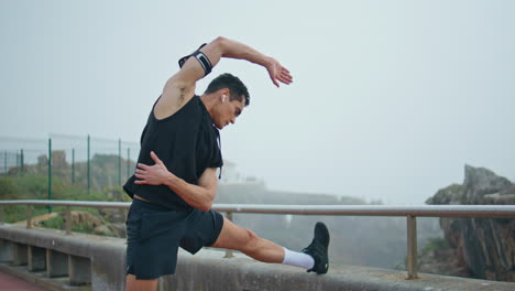 man runner stretching body on street. muscular athlete warming up before race