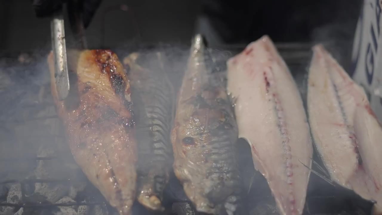 Pesce fresco e filetti che grigliano su un barbecue fumante