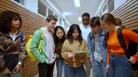 group of students looking at a tablet in a hallway