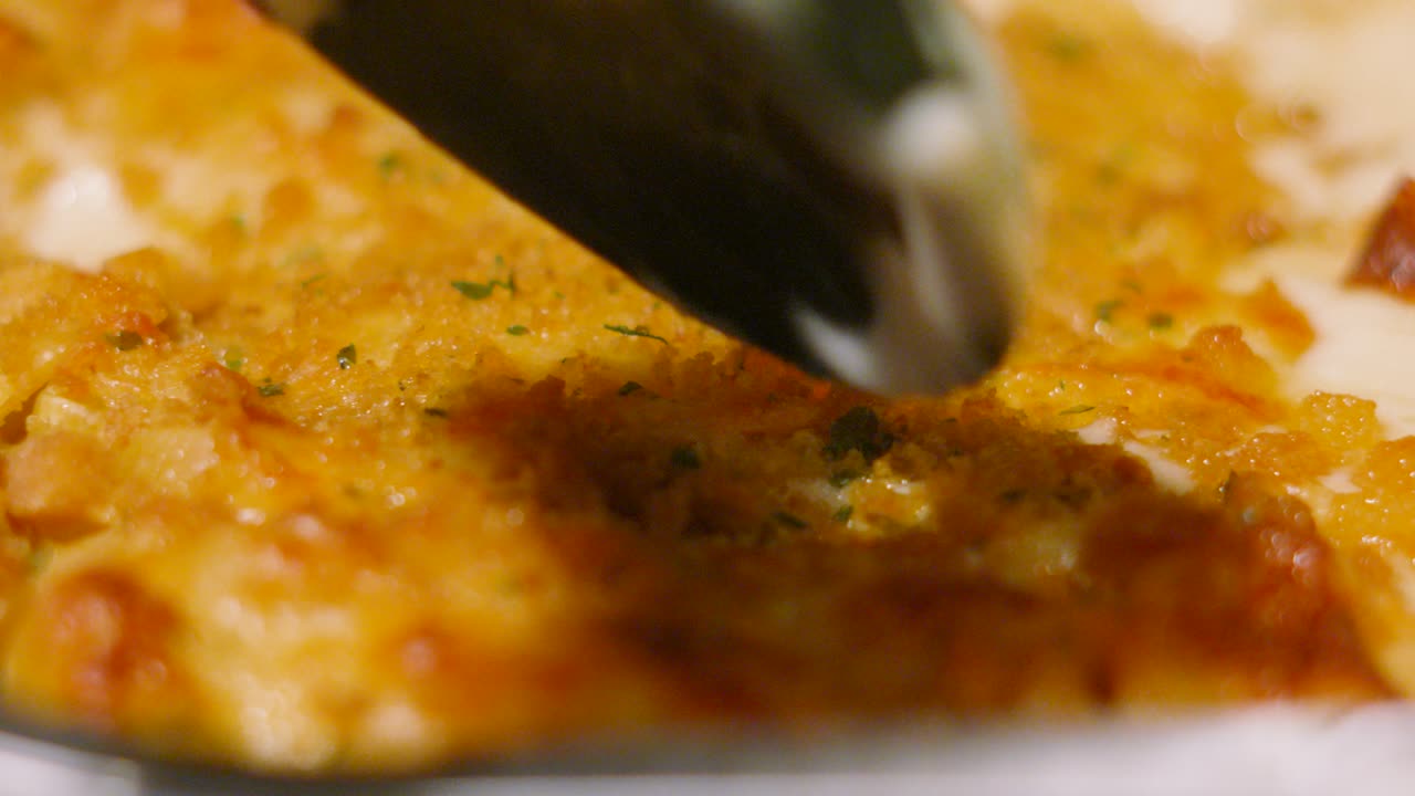Crispy Top of Macaroni Cheese with Serving Spoon Coming Down and Tapping Top Getting Ready to Serve. Pasta Based Dinner Food Meal Footage