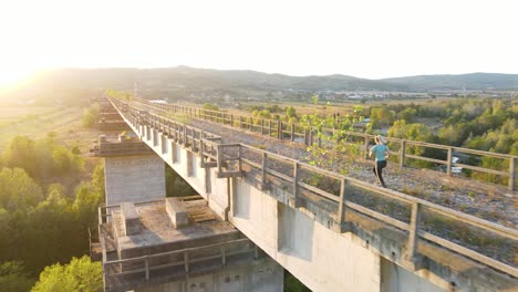 girl jogging on bridge at sunset in 4k, pan shot