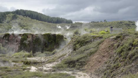 a wide shot of a father and son taking a selfie at a lookout over a steaming crater at craters of the moon in taupo, nz