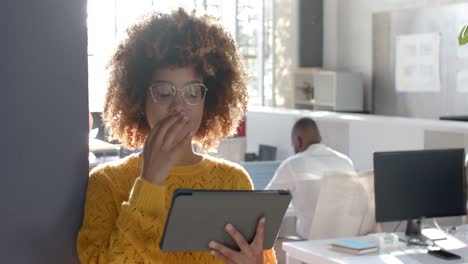 Portrait-of-happy-biracial-casual-businesswoman-with-tablet-in-sunny-office,-copy-space,-slow-motion