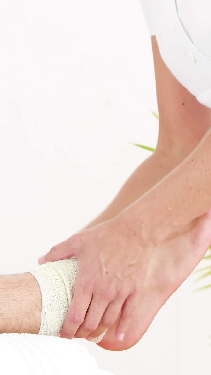 Fisioterapista che fascia una caviglia infortunata con una benda