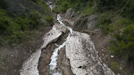 Low-altitude-drone-flight-over-a-snow-filled-canyon-after-the-thaw-began