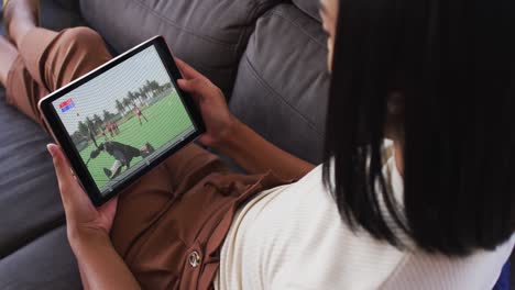 composite of woman sitting at home on couch watching hockey match on tablet