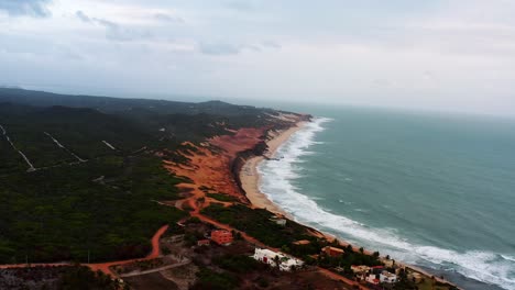 Amplia-Toma-Aérea-De-Drones-De-La-Pequeña-Ciudad-Costera-Escondida-De-Sibauma-Cerca-De-Pipa-En-El-Norte-De-Brasil-Con-Playas-Tropicales-De-Arena-Naranja-Brillante-Y-Caminos-De-Arena