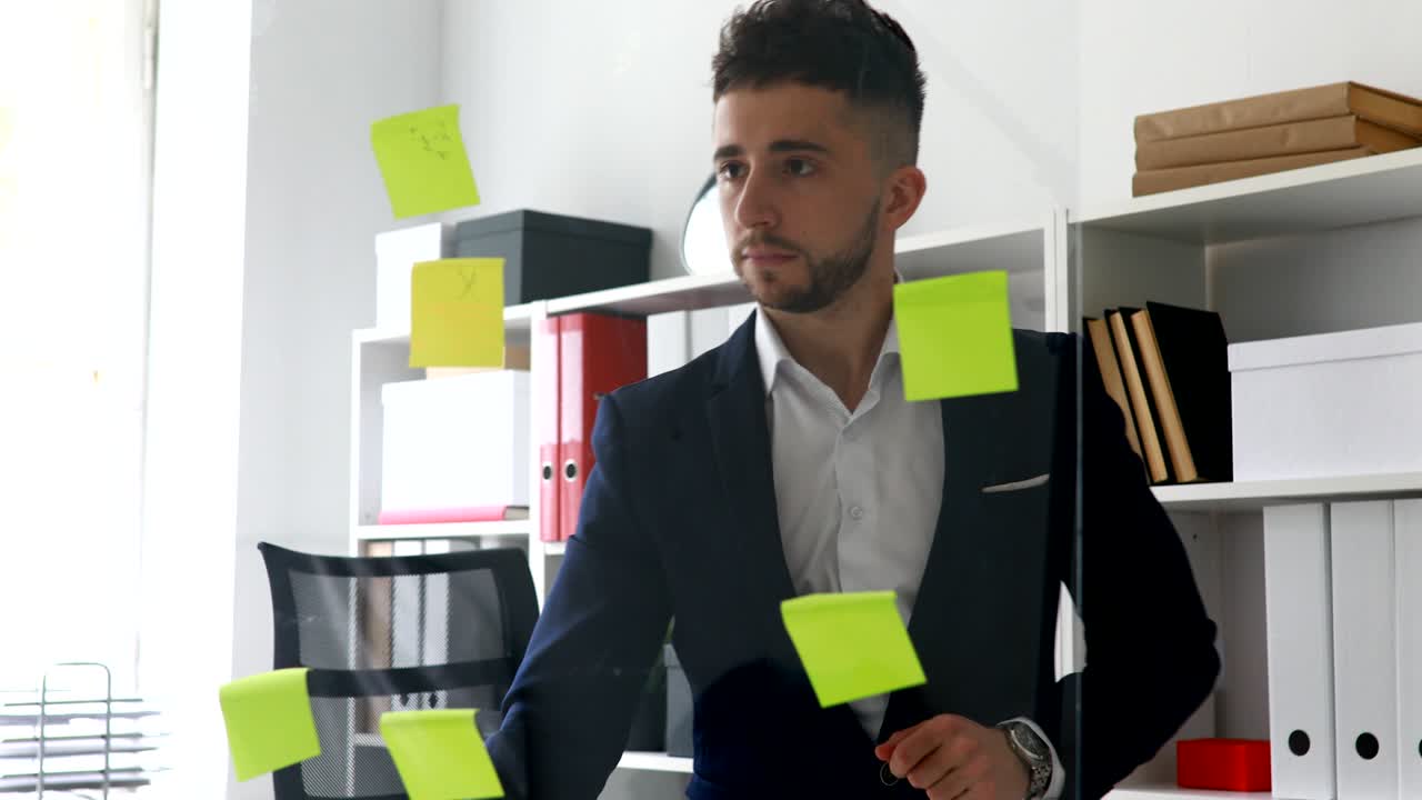 Empresário fazendo anotações em post-its em parede de vidro