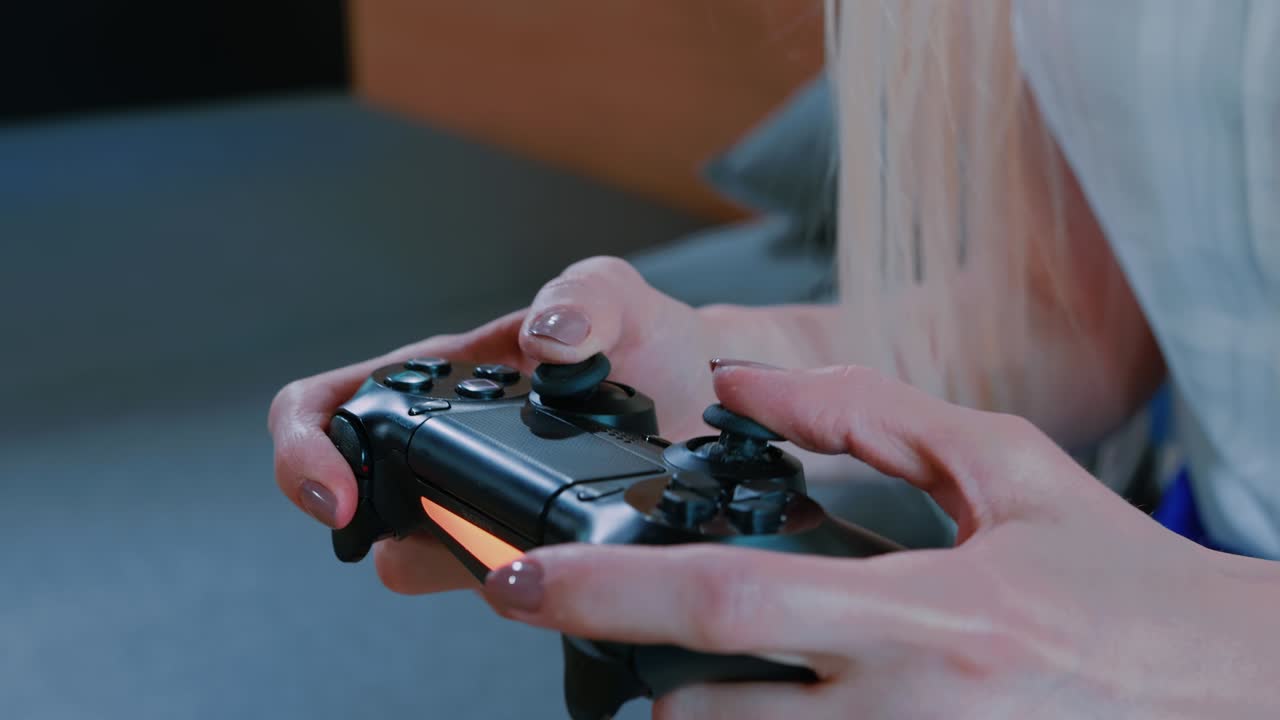 mujer relajada jugando a la consola en el interior. mujer joven casual relajándose en el sofá y jugando videojuegos con gamepad en un interior moderno