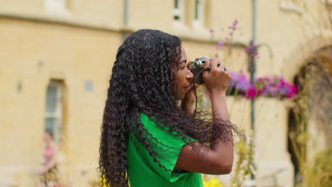 Female-Tourist-With-Camera-On-Vacation-In-Oxford-UK-Exploring-City-Walking-Along-Broad-Street-Taking-Photos-6