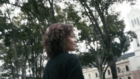 Sweet-female-in-a-suit-with-curly-hair-walks-looking-around-in-the-city-of-Bogota