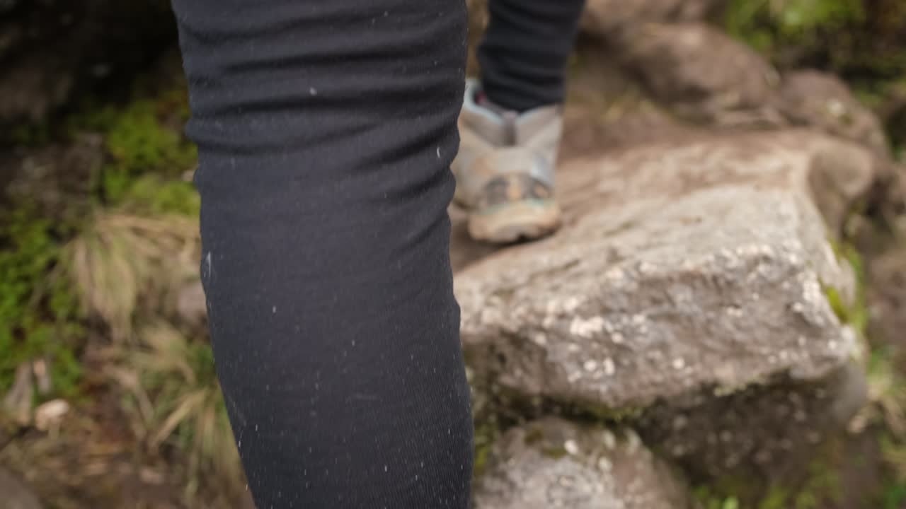 Close-up of the legs of a Girl walking with trekking poles on a mountain path