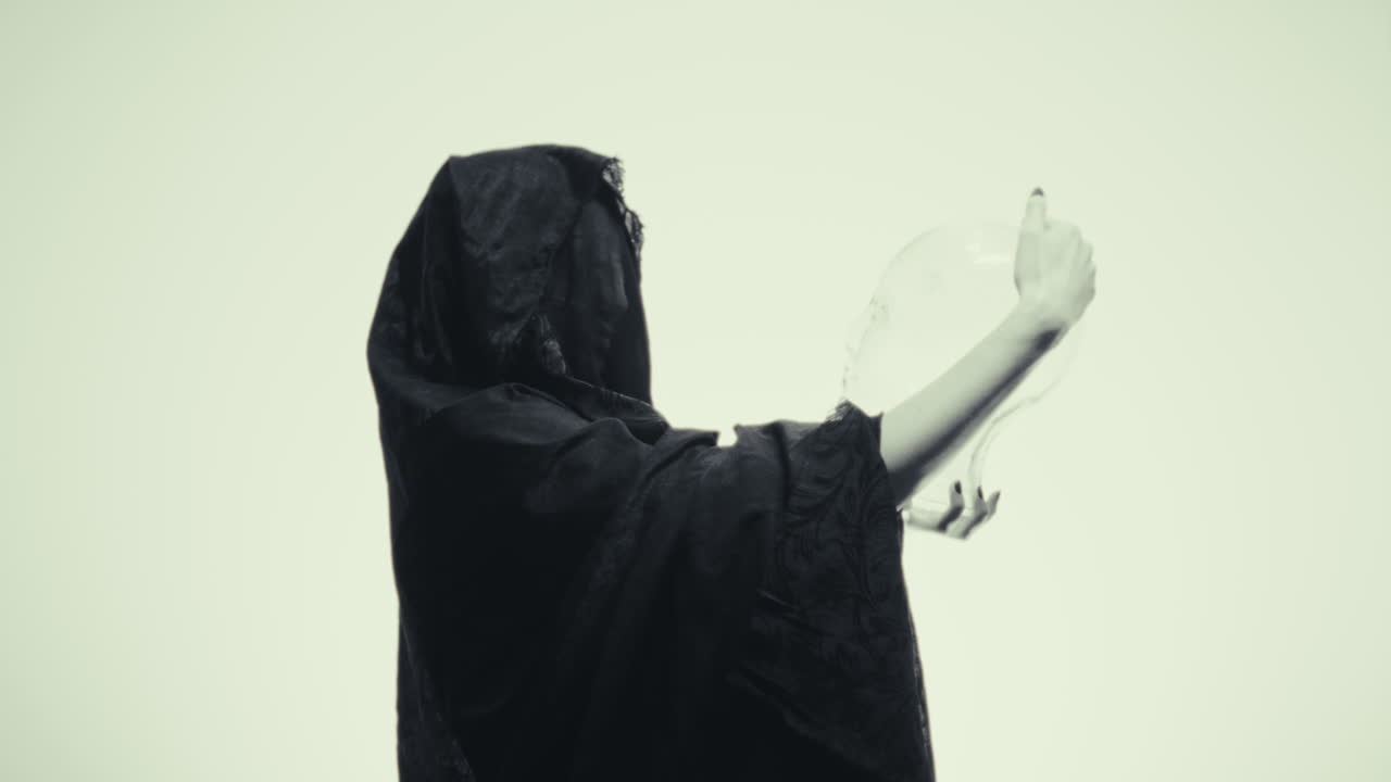 Woman in Black Cloak with Glass Skull