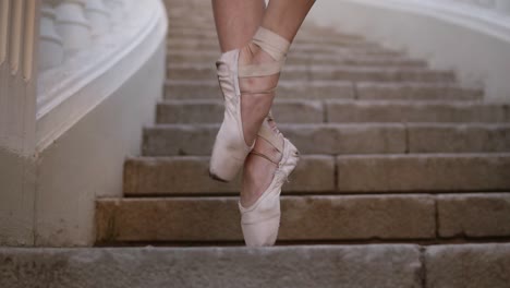 close up of a woman's feet in beige pointe. young, beautiful ballerina demonstrating ballet movements. black tutu. upward footage