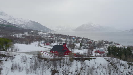 Rote-Holzkirche-In-Der-Stadt-Kåfjord,-Olderdalen,-Norwegen-Im-Winter---Drohnenaufnahme-Aus-Der-Luft