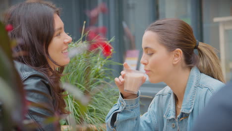 happy same sex female couple meeting and sitting outdoors at coffee shop together