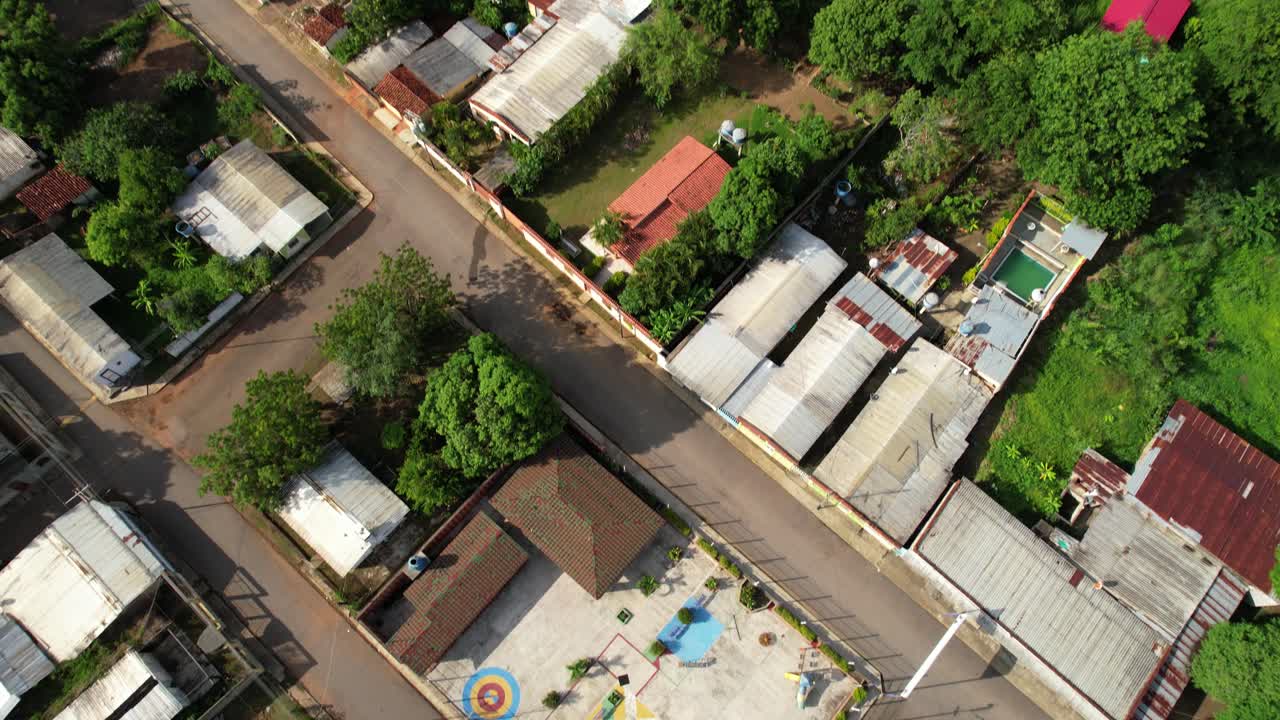 Aerial tilt-down from lush tropical forest to a schoolyard sports court in Parapara village, Guárico, Venezuela,