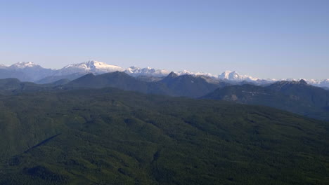 lush and rocky mountains covered with snow - beautiful landscape over sunshine coast in british columbia, canada - wide aerial shot