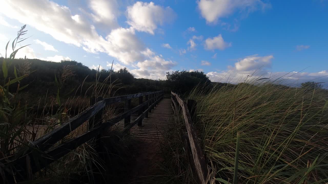 pasarela de playa de madera de dolly de lapso de tiempo con hierba larga y nubes que soplan