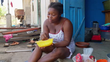 Ghanaian-black-woman-eating-with-her-hands,-enjoying-banku,-typical-Ghanaian-dish