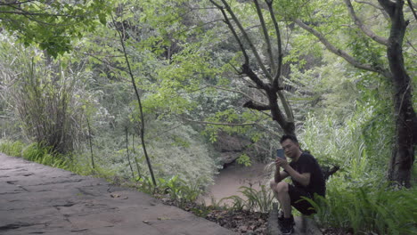 un hombre descansa y toma fotos en el bosque