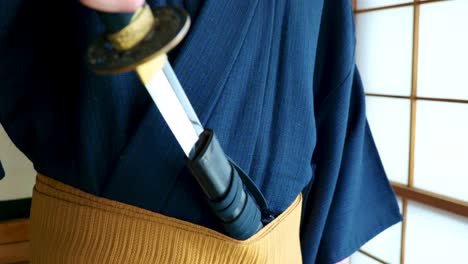 a man in a traditional japanese kimono with a samurai's katana sword in an old traditional japanese house in slow motion