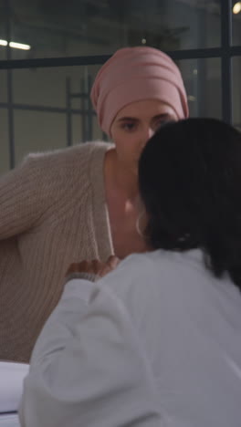 vertical video of serious young woman patient wearing headscarf undergoing chemotherapy treatment for breast cancer meeting with oncologist or doctor in hospital 1