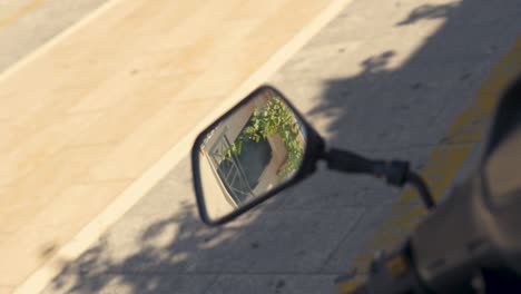 a slow motion moving shot of a moped's mirror reflecting the rooftops of the greek street behind it