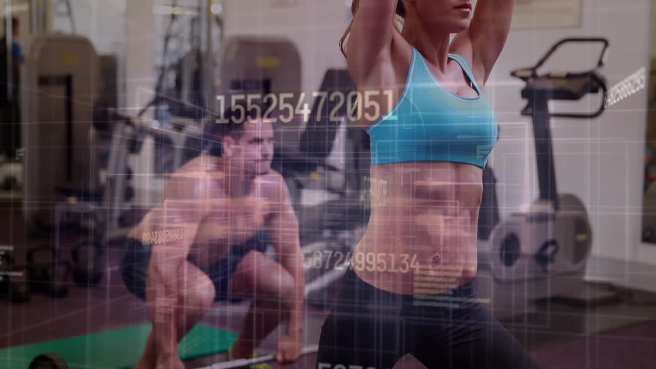 Workout partners raising arms and squatting on green mat in gym, displaying fitness data overlay