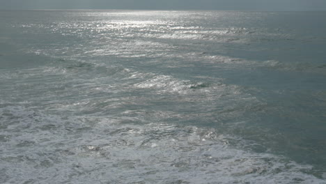 sun-casting-rare-silver-light-as-it-reflects-on-waves-in-wild-sea-during-dramatic-but-beautiful-morning