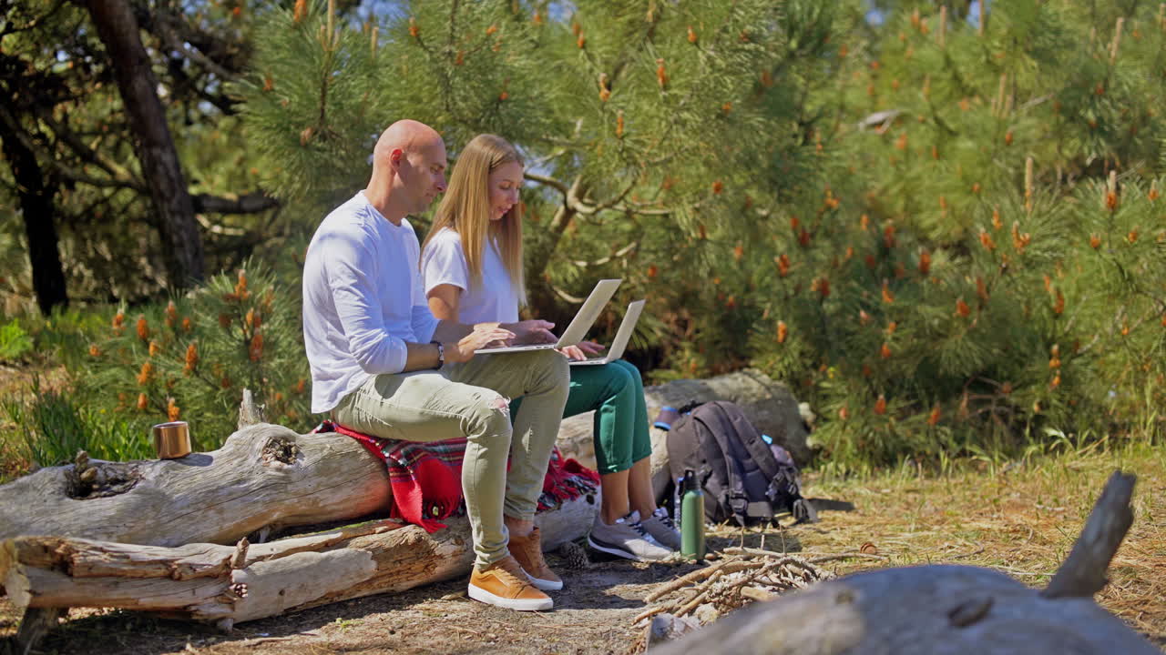 pareja usando computadoras portátiles en el bosque