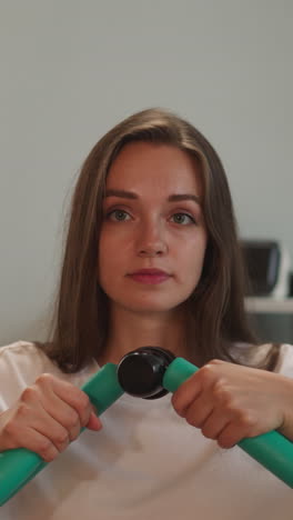 young woman uses training apparatus to stretch arms muscles. person with disability sits in wheelchair doing effective exercise for body closeup