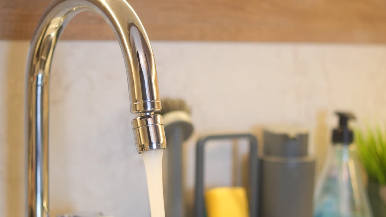 Primo piano di un rubinetto da cucina con acqua che scorre