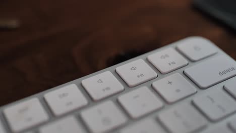 Man-hand-pressing-volume-down-button-on-a-white-keyboard