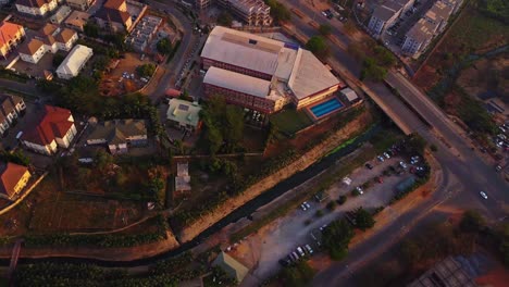 beautiful aerial overview of a wealthy neighborhood in abuja, nigeria with a large sports hall with an outdoor swimming pool