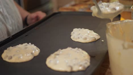 Mujer-Coloca-Masa-Para-Panqueques-Con-Trocitos-De-Chocolate-En-Una-Sartén-Calentada-A-Cámara-Lenta