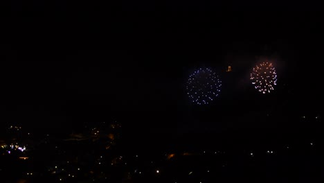 Celebration-with-many-golden-and-sparkling-fireworks,-over-a-mountain-town,-at-night