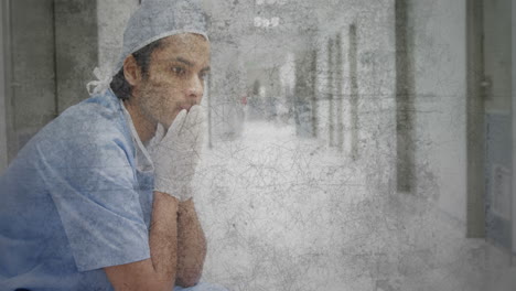 superposición rayada texturizada contra el trabajador de salud masculino caucásico estresado sentado en el hospital