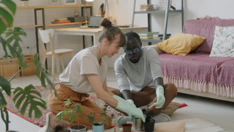 diverse couple repotting houseplants in living room