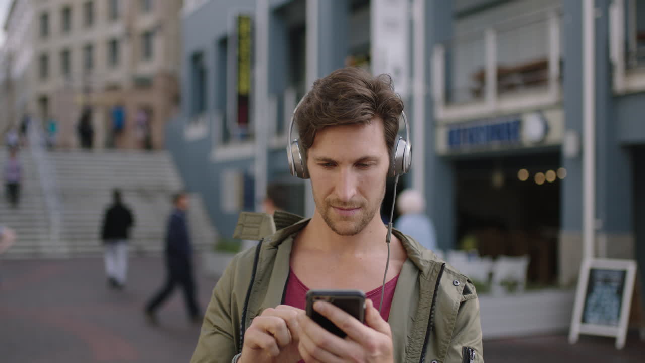retrato de un joven atractivo hombre caucásico en una concurrida calle urbana con auriculares escuchando música disfrutando del estilo de vida
