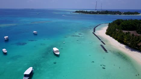 The-Cook-Islands---Boats-On-The-Bright-Blue-Sea-Waters-With-The-Scenery-Of-Two-Lush-Islands-And-White-Sand---Wide-Shot