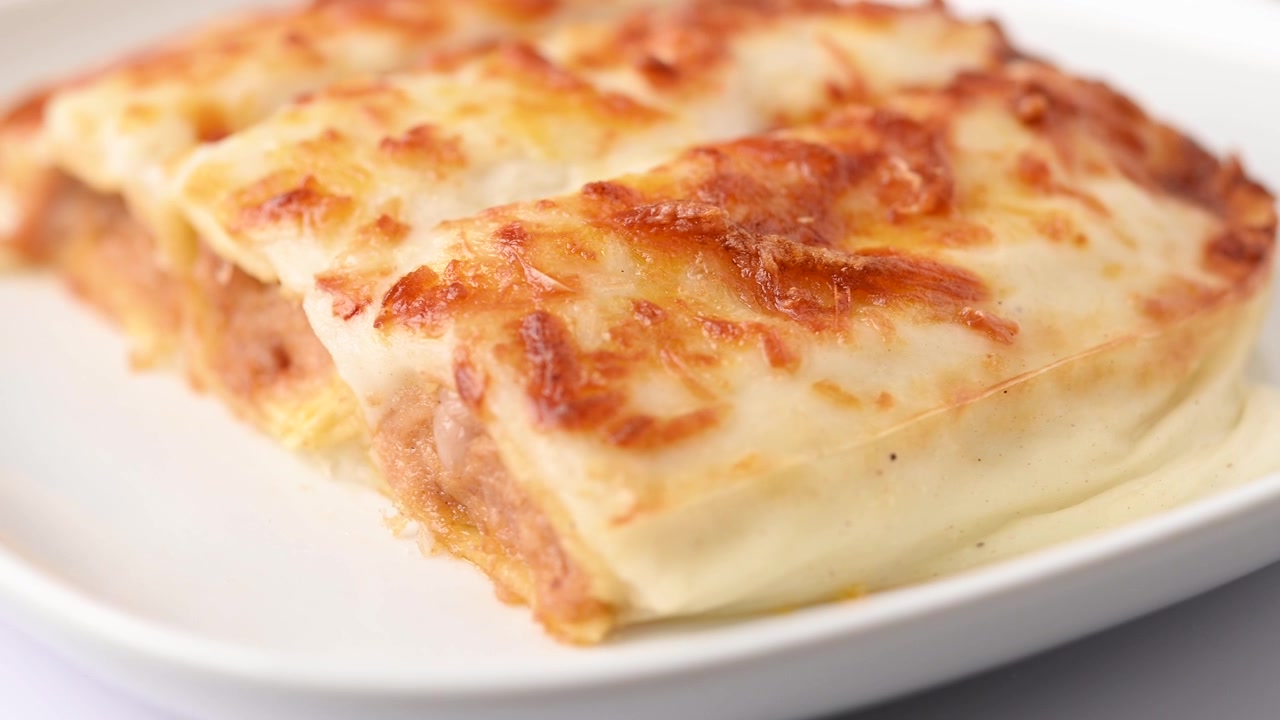 Cannelloni di carne al forno con formaggio e salsa besciamella.
