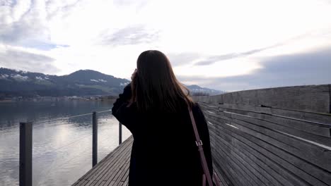 following shot of a young asian woman doing her hair while walking on a wooden pier in slow motion in rapperswil switzerland