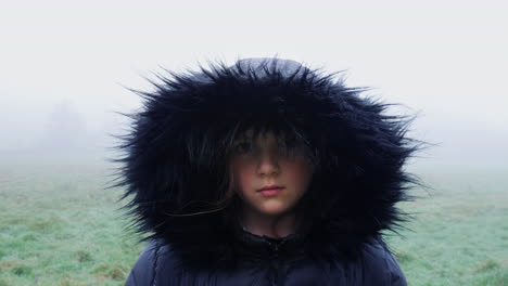 portrait of a hooded girl on a cold misty morning in the countryside